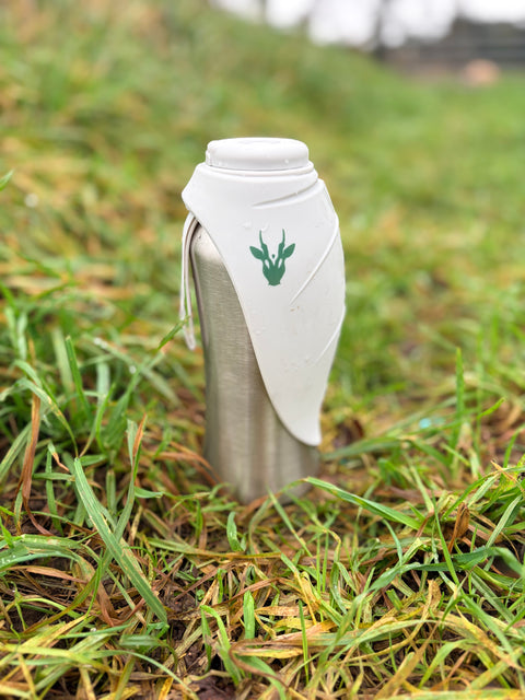 White bottle with Muntjac logo on grass
