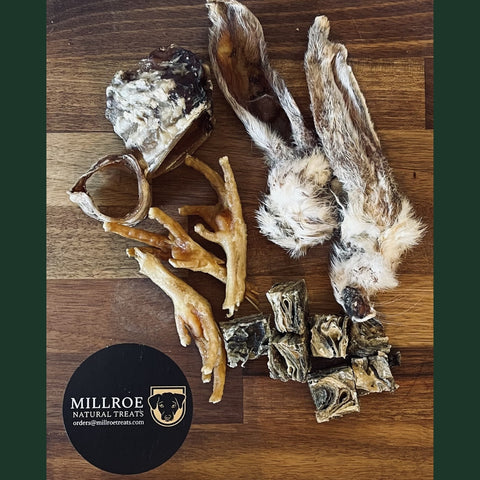 Assorted pet treats on a wooden surface with Millroe Natural Treats logo.