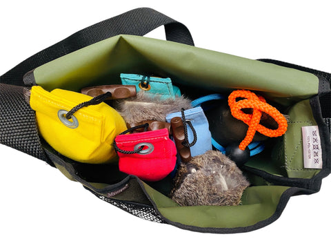 Green bag with various items including a yellow dummy, red dummy, and orange rope on a khaki dummy on a white background.